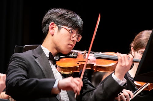 A Man in Black Suit Playing a Violin