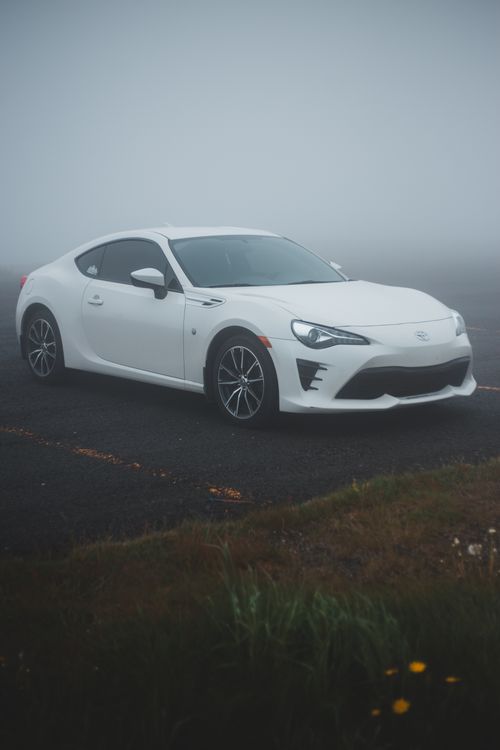 Free Modern car parked on empty asphalt road near green grass in countryside in foggy day Stock Photo