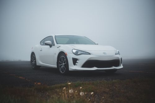 Free Asphalt road in green field with parked modern white automobile in foggy weather Stock Photo