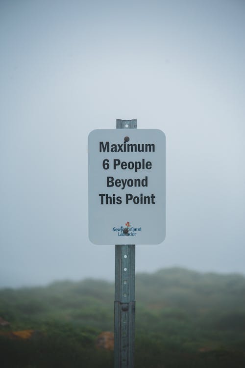 Free Metal warning sign in front of breathtaking landscape with hills in foggy day Stock Photo
