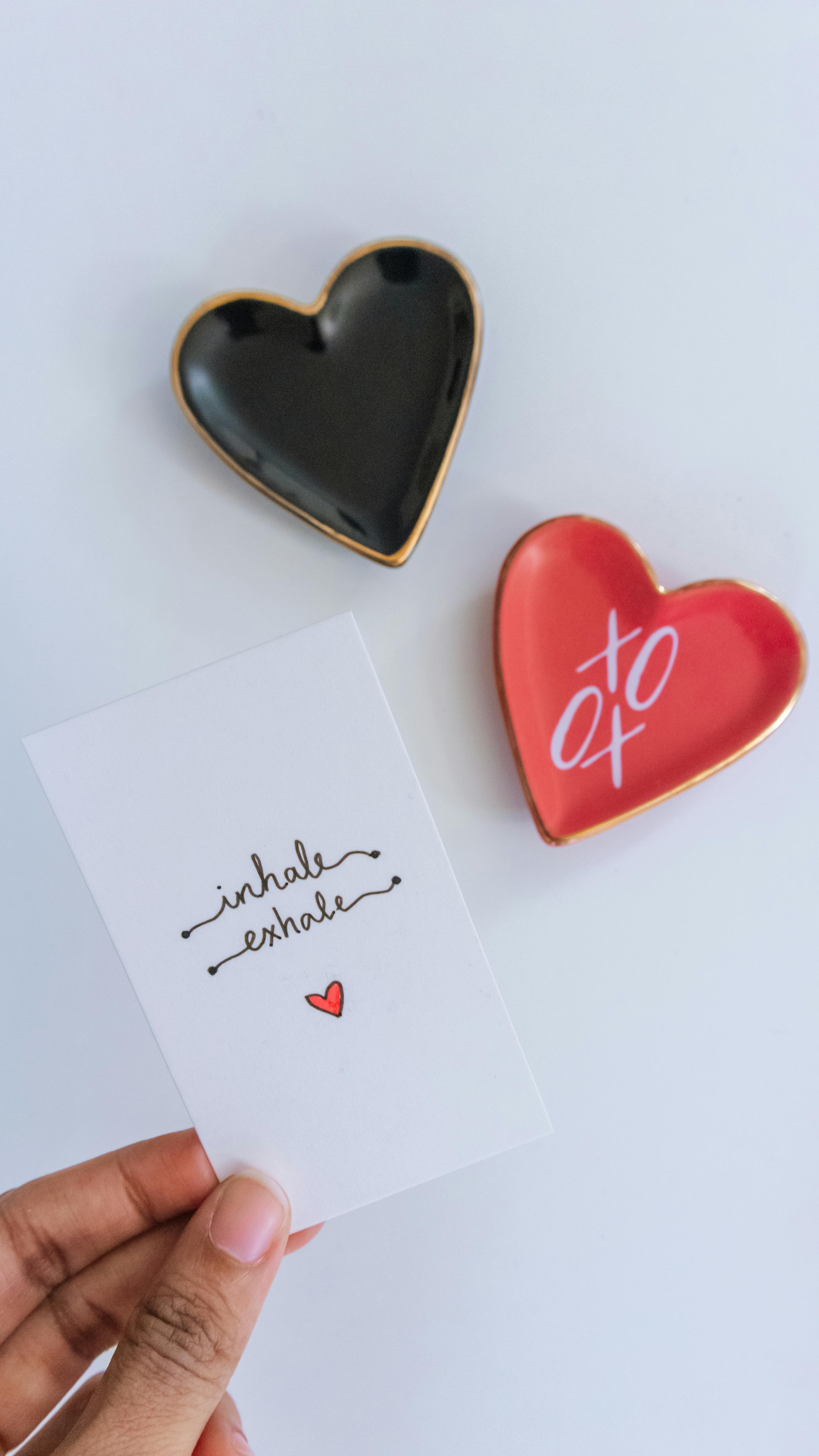 Hand holding a card with heart-shaped plates, perfect for Valentine's Day or love concept photos.