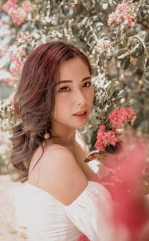 这幅迷人的肖像画描绘了一位被盛开的粉红色花朵包围的女性，唤起了优雅与自然之美