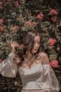 Woman in White Dress Posing By a Bush with Pink Flowers