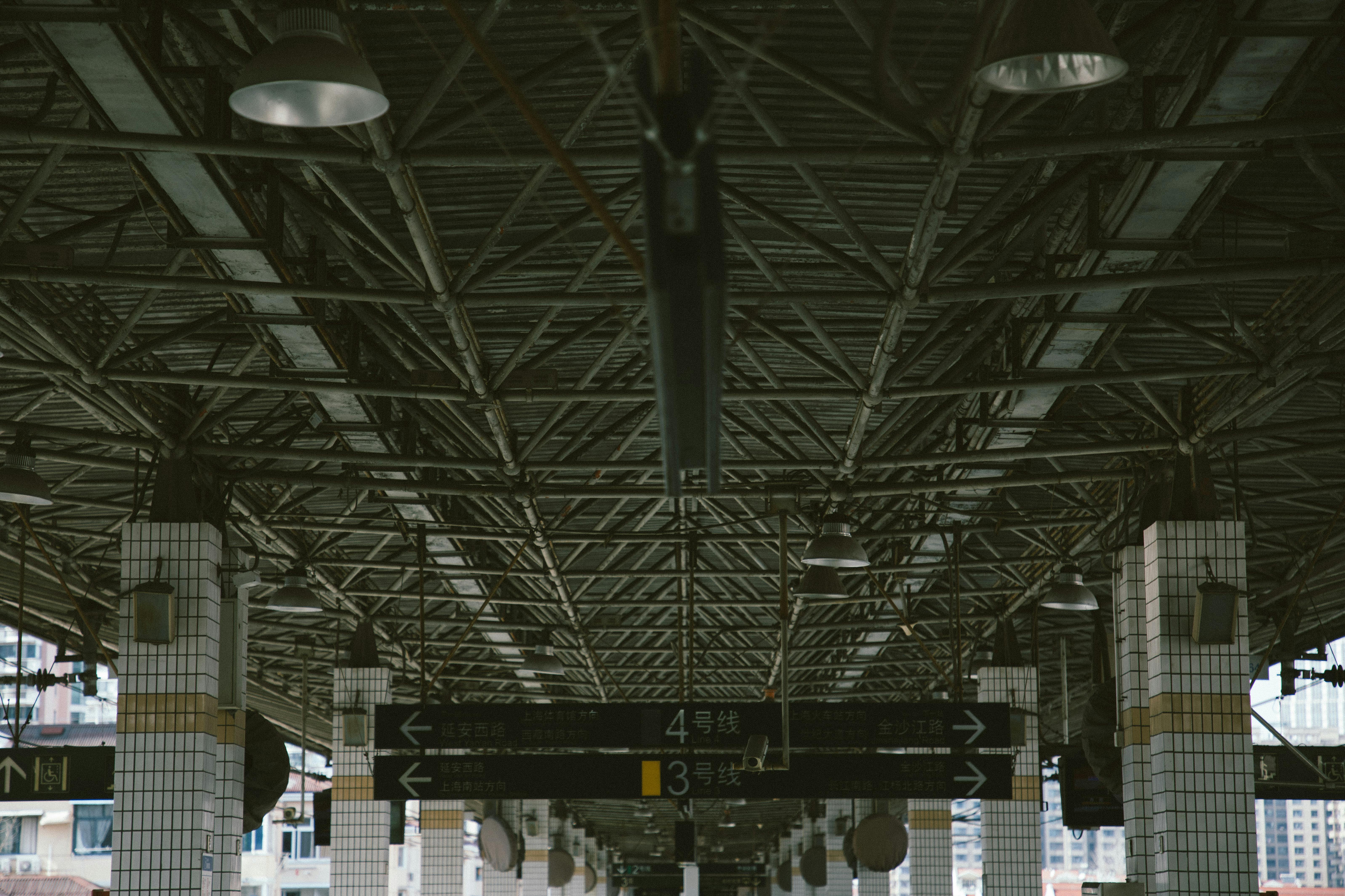 Low-angle view of industrial metal ceiling in a train station with signs.