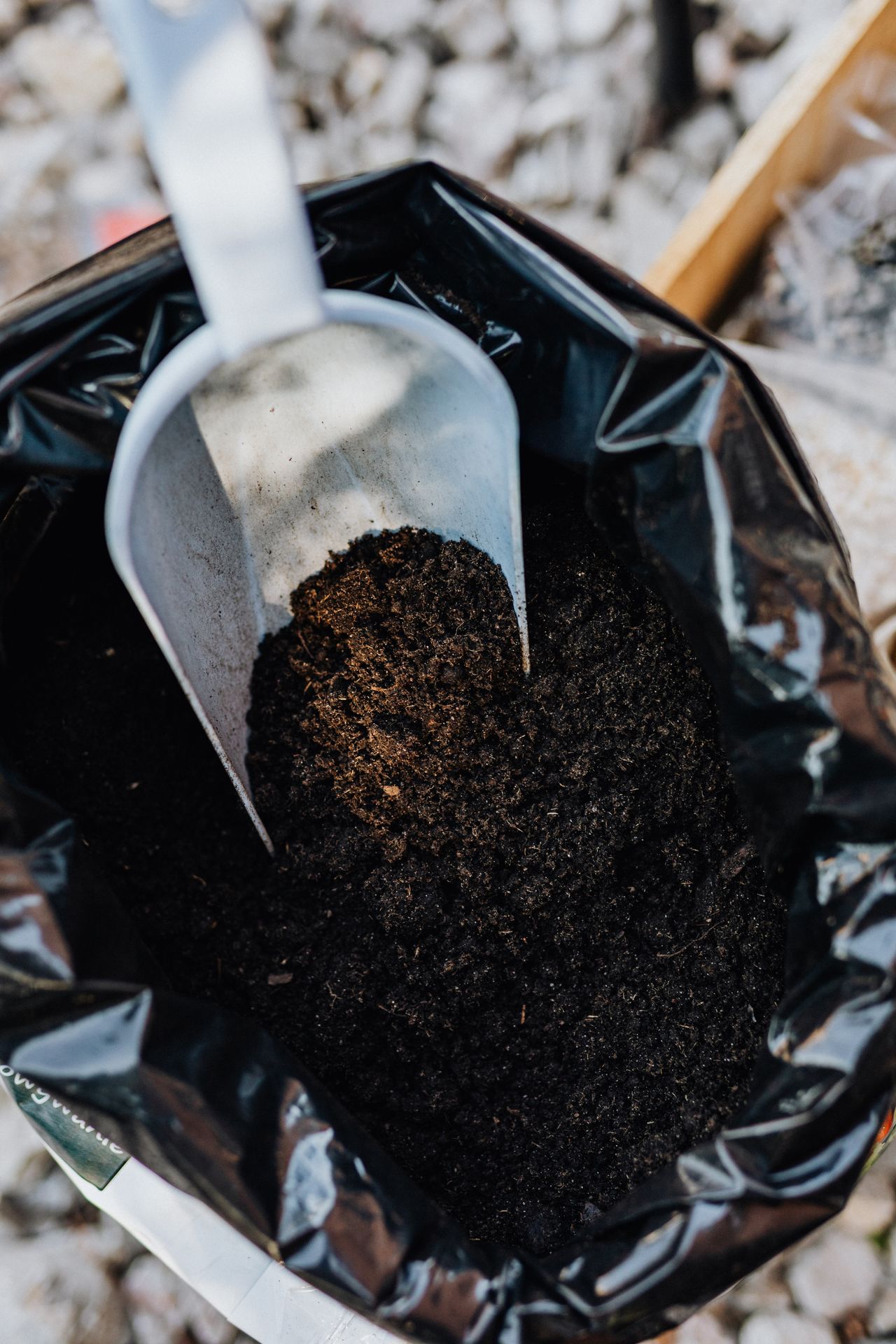 Garden trowel scooping dark mulch from an open bag