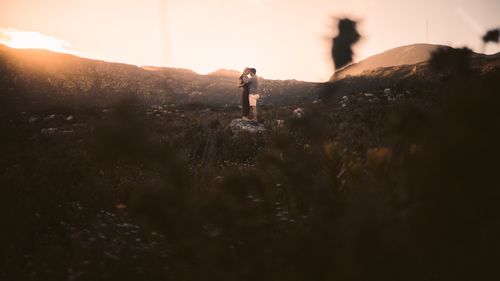 Free A couple embracing on rocks surrounded by nature during a beautiful sunset. Stock Photo