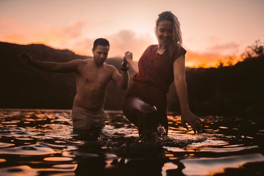 日落时分，一对夫妇在温暖的夏夜涉水过湖