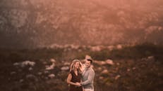 幸福的情侣在温暖的日落灯光下在户外享受风景优美的山景