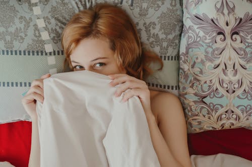 Calm woman lying under blanket on bed