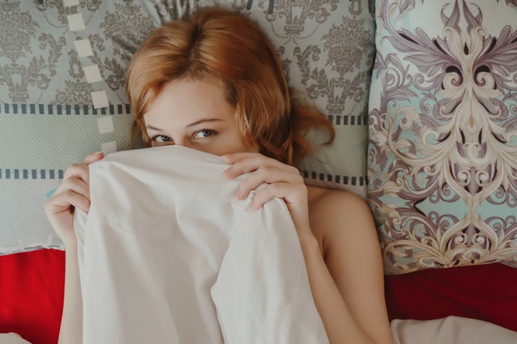 Calm Woman Lying Under Blanket On Bed