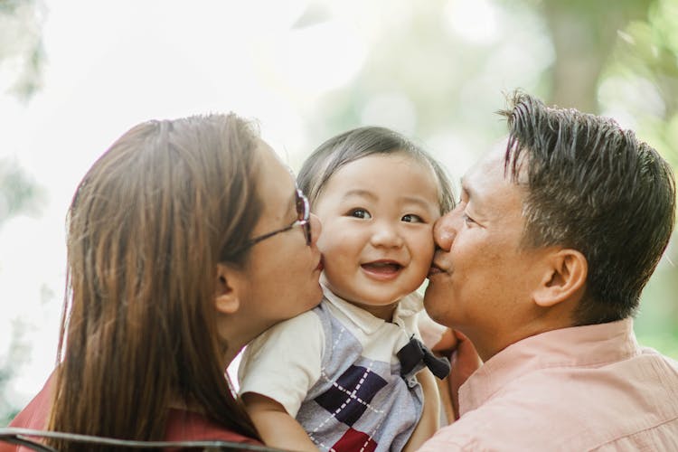 Man And Woman Kissing A Baby