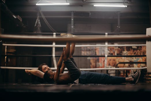 A young boy stretches with a trainer in an indoor gym setting, focusing on fitness and exercise.