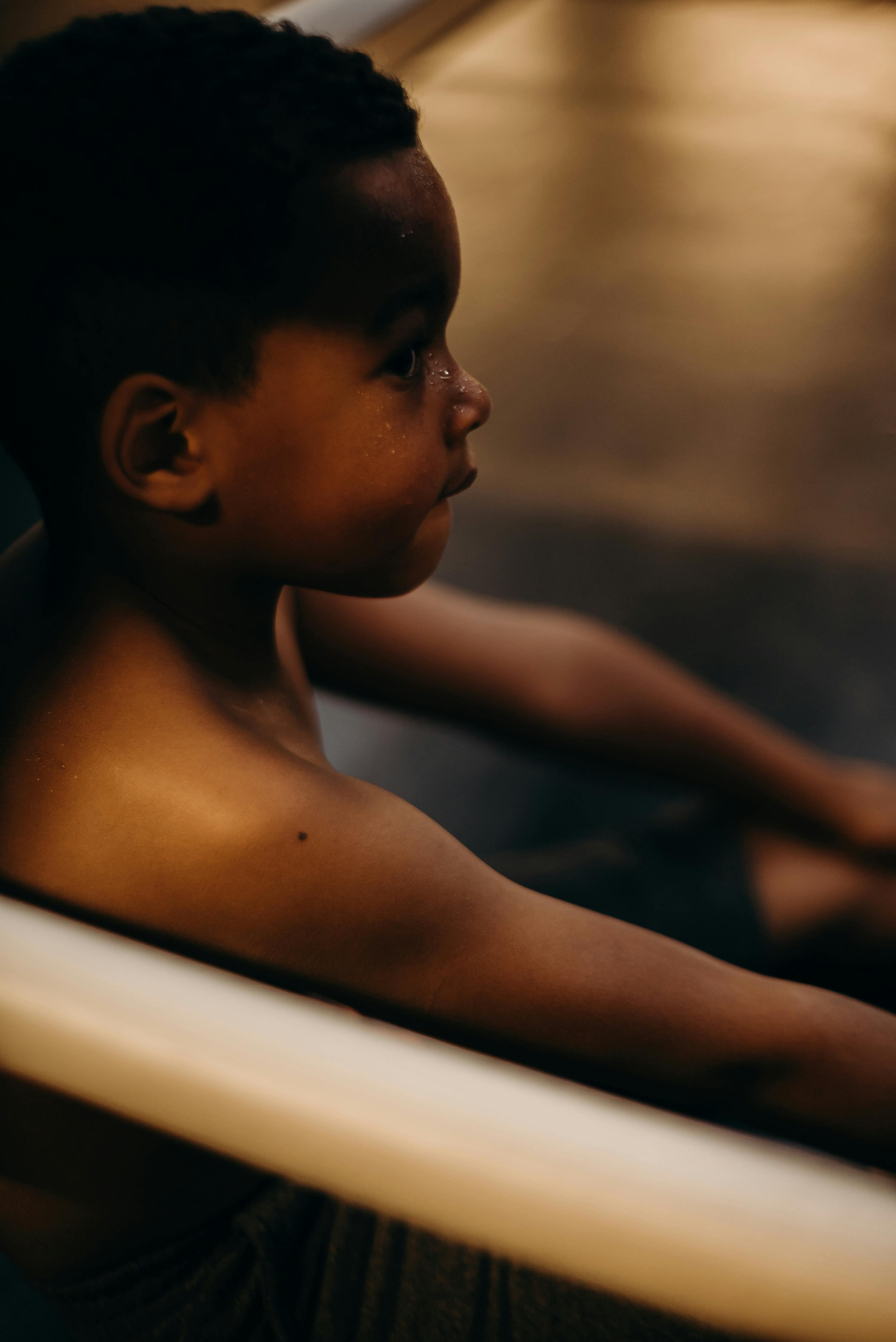A young boy sitting inside a gym, deep in thought, highlighting youthful determination.