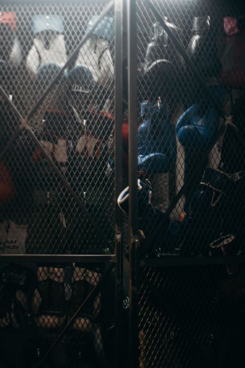 Free A dimly lit locker containing boxing gear including gloves and helmets in a gym setting. Stock Photo