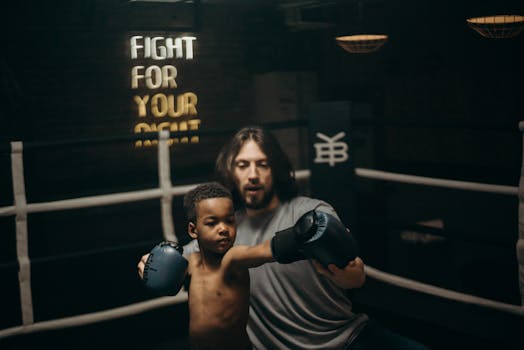 A child practices boxing under the guidance of a coach in an indoor gym setting.