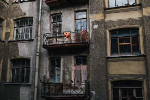 Free Aged exterior of a building with historic architecture featuring worn balconies and vintage windows. Stock Photo
