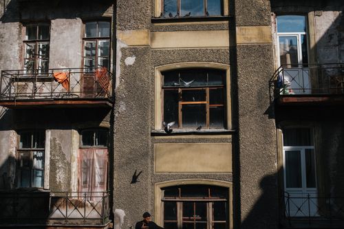 Free Aged European facade with balconies and pigeons, showcasing vintage architecture under daylight. Stock Photo