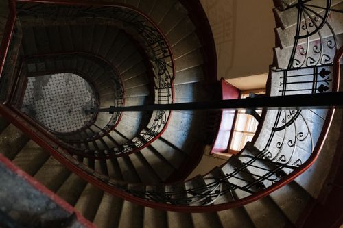 Free Aerial view of a spiral staircase with wrought iron railings in a vintage-style interior. Stock Photo