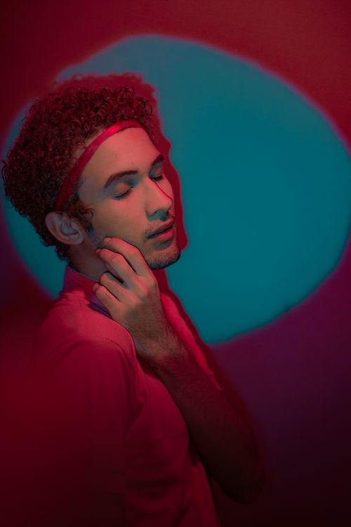 Free Vibrant artistic portrait of a man under red and blue lighting with a serene expression. Stock Photo