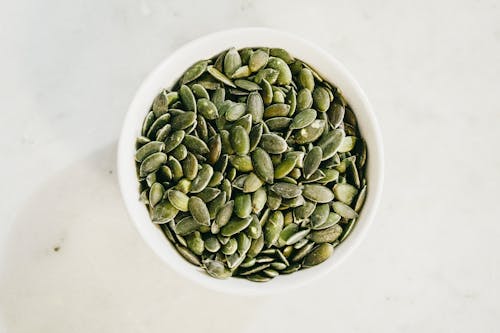 Free Top View of Pumpkin Seeds in a White Bowl Stock Photo