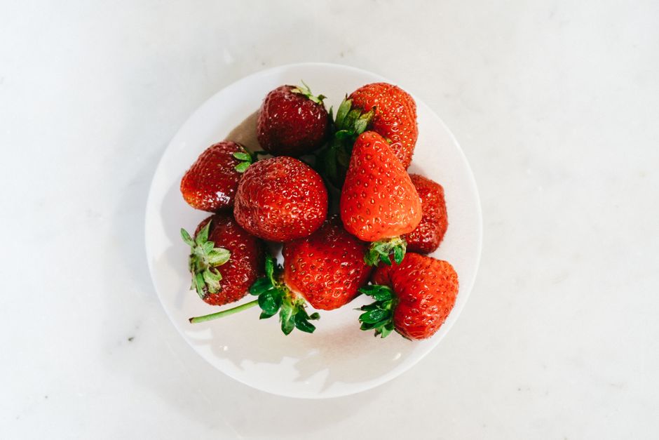A top view of fresh, juicy strawberries in a white bowl, perfect for healthy eating visuals.