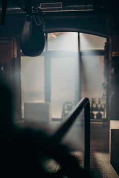 A sunlit gym interior with a punching bag and beams of light streaming through windows.