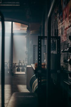 A dark and atmospheric gym interior showcasing weights and fitness equipment with dramatic lighting.