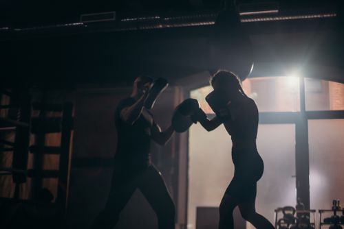 Free Silhouetted boxers sparring during an intense training session in a dimly lit gym. Stock Photo