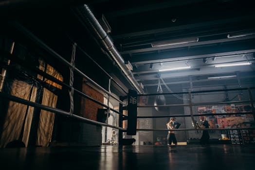 Two boxers sparring in a dimly lit gym, practicing punches with dedication.