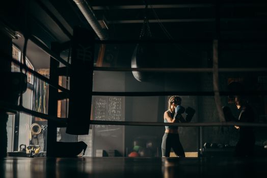 Focused female boxers sparring during a training session in a dimly lit gym.
