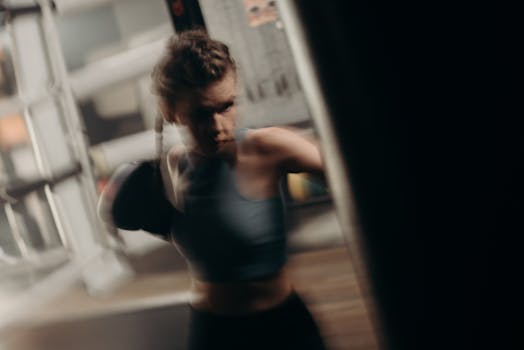 Blurred motion of a female boxer practicing punches in a gym setting.