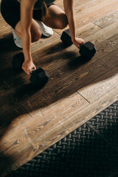 Person lifting dumbbells during a home workout, photo by cottonbro studio on Pexels
