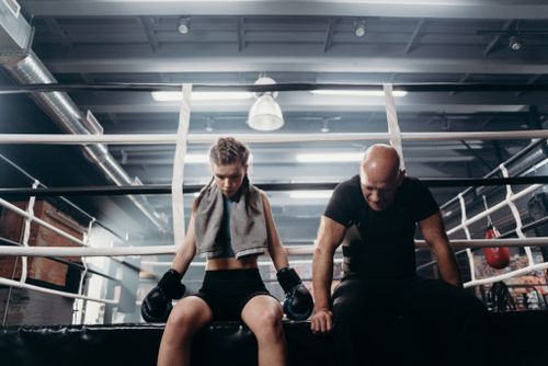 Free Female boxer and coach resting in a boxing ring after an intense training session. Stock Photo