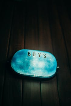 在昏暗的室内环境中，一个发光的男孩厕所标志投射出柔和的蓝光，镜头给了它一个特写