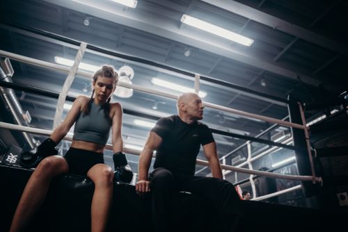 Free Female boxer and male coach resting in a boxing ring post-training session. Stock Photo