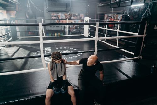 Free Female boxer receiving encouragement from coach in the boxing ring setting. Stock Photo
