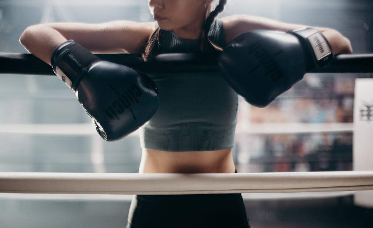 Free Woman in Black Sports Bra and Black Shorts Holding Black and White Boxing Gloves Stock Photo
