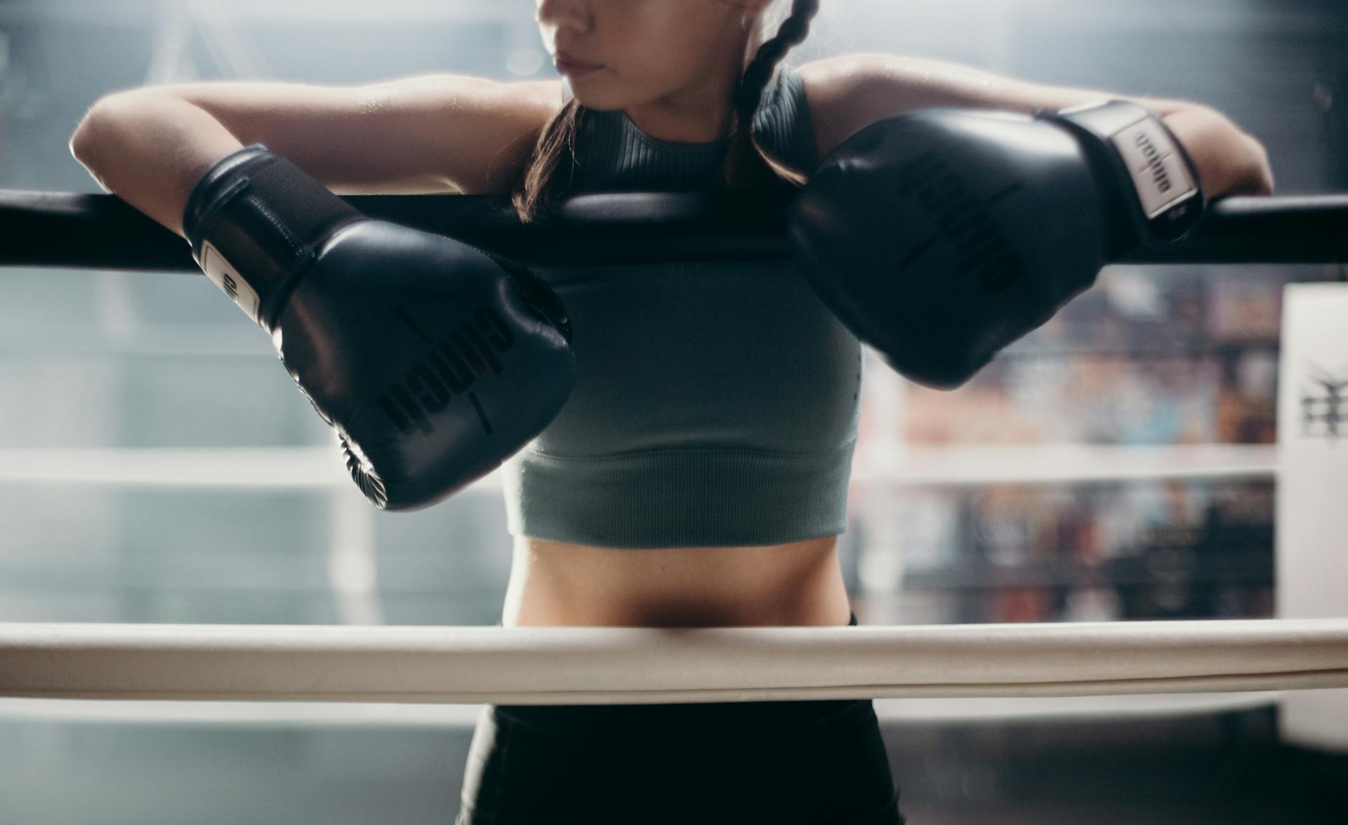 Woman in Black Sports Bra and Black Shorts Holding Black and White Boxing Gloves