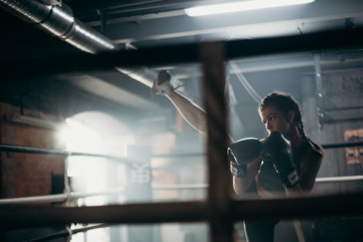 A female boxer in a gym practicing kickboxing moves with focus and strength.