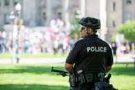 Police officer on bicycle standing in front of protesting crowd