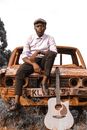 Man with Guitar on Car Wreckage