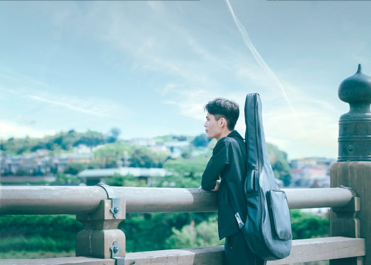 A Man Carrying A Guitar