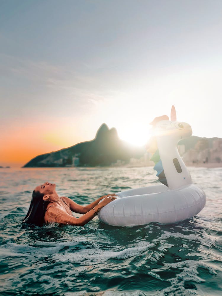 Woman Swimming In The Sea With Inflatable Unicorn