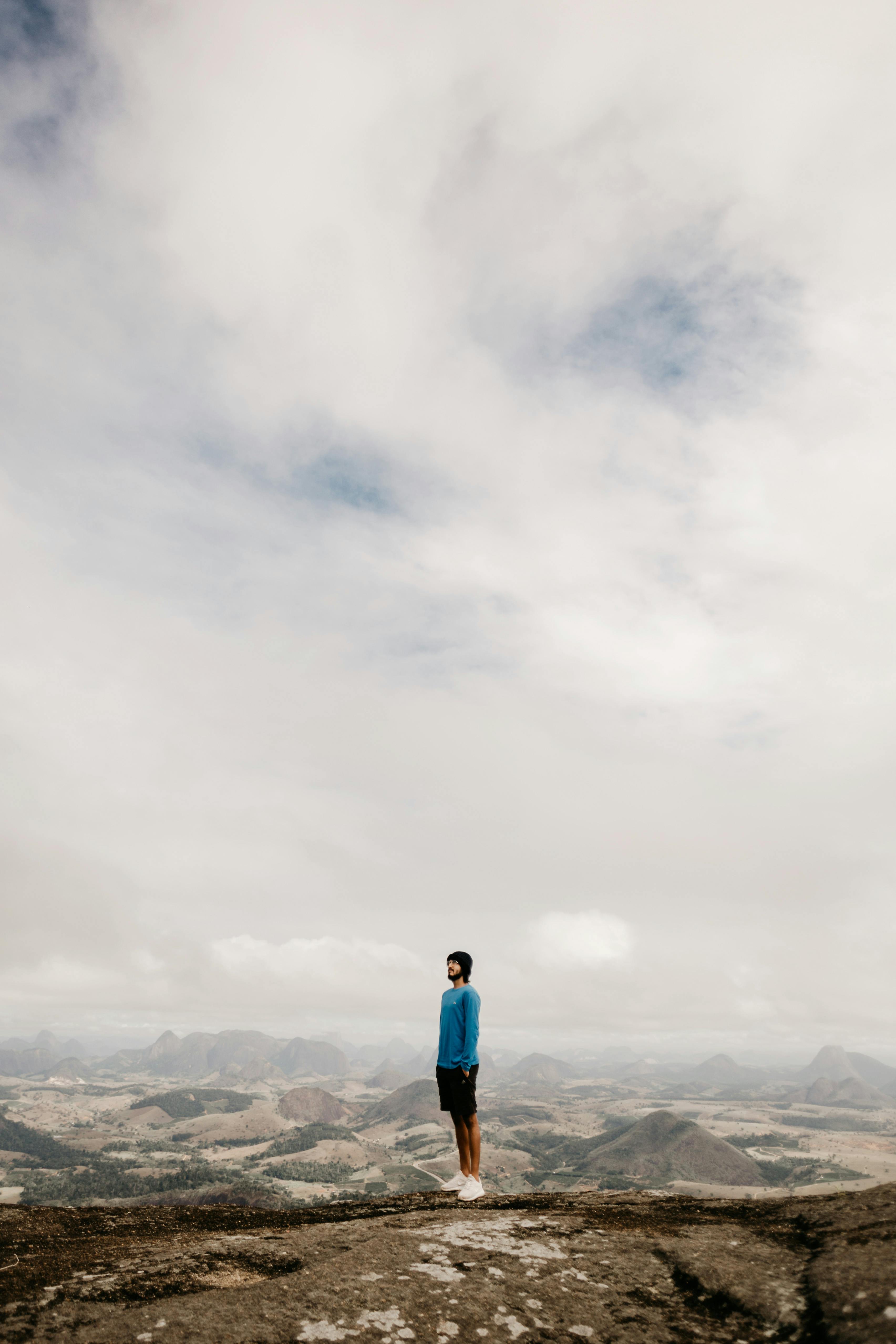 anonymous man standing on mountainous terrain