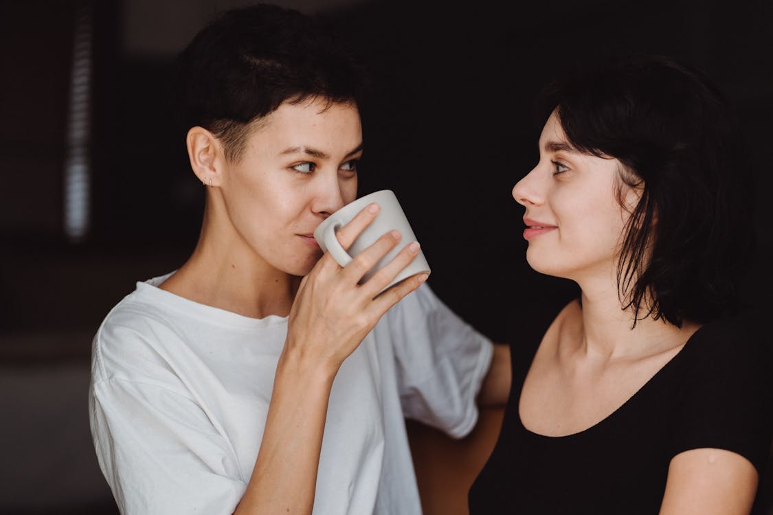 Free Woman Drinking Coffee and Looking at Another Woman Stock Photo