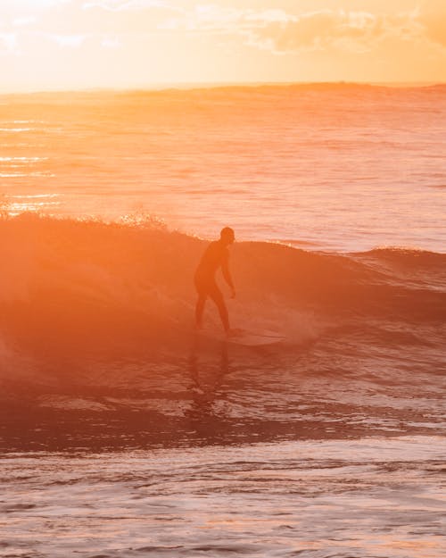 A Man Surfing During Sunset