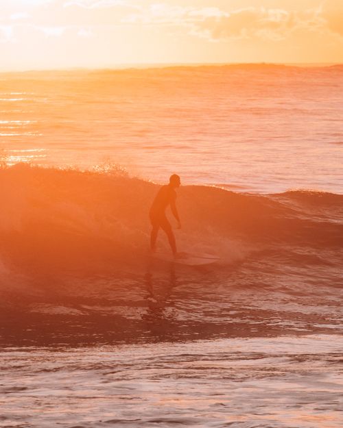 Free Silhouetted surfer riding a wave during a stunning sunset in South Australia. Stock Photo