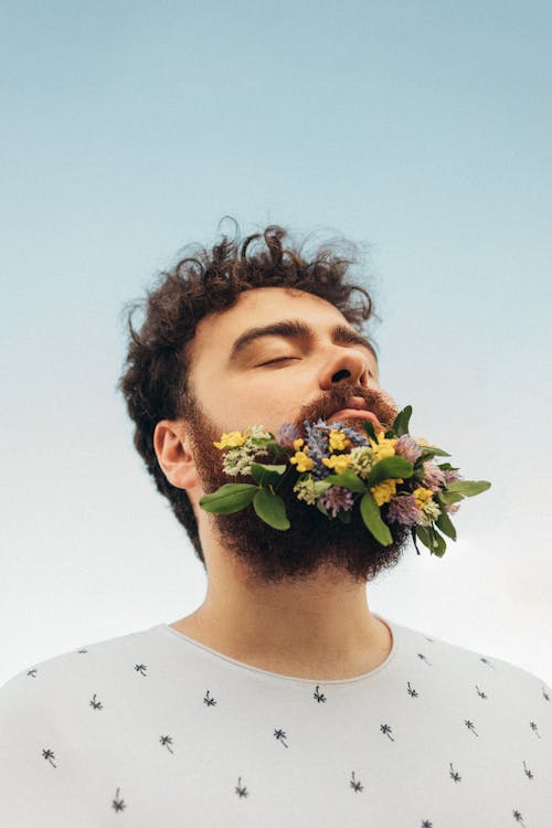 Low Angle Portrait of a Man with Wildflowers in His Beard