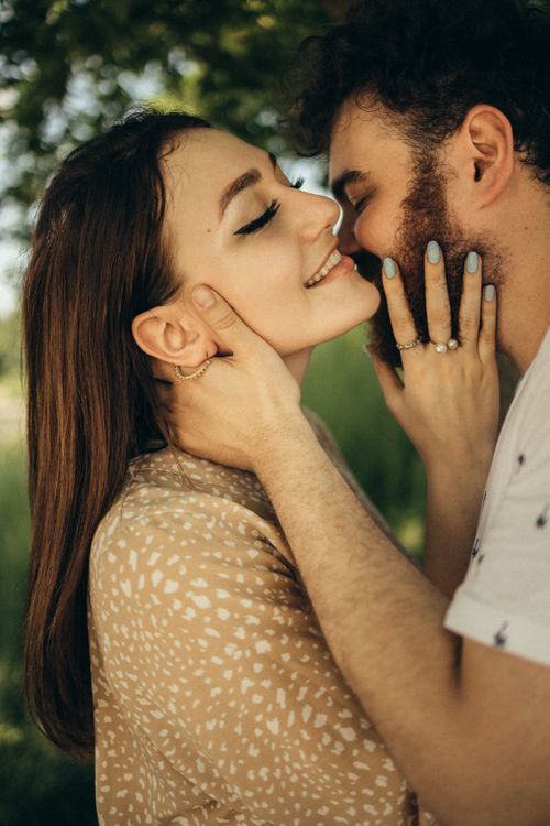 Free A loving couple shares a tender kiss in a serene outdoor setting, capturing the essence of romance. Stock Photo