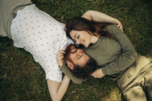 Man and Woman Lying on Green Grass Field